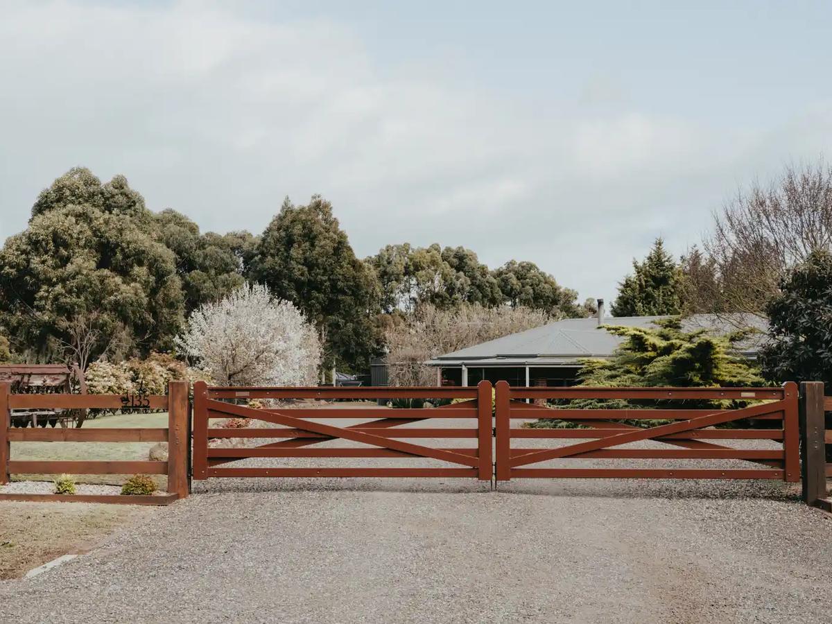 Timber post and rail entry gate across a gravel driveway