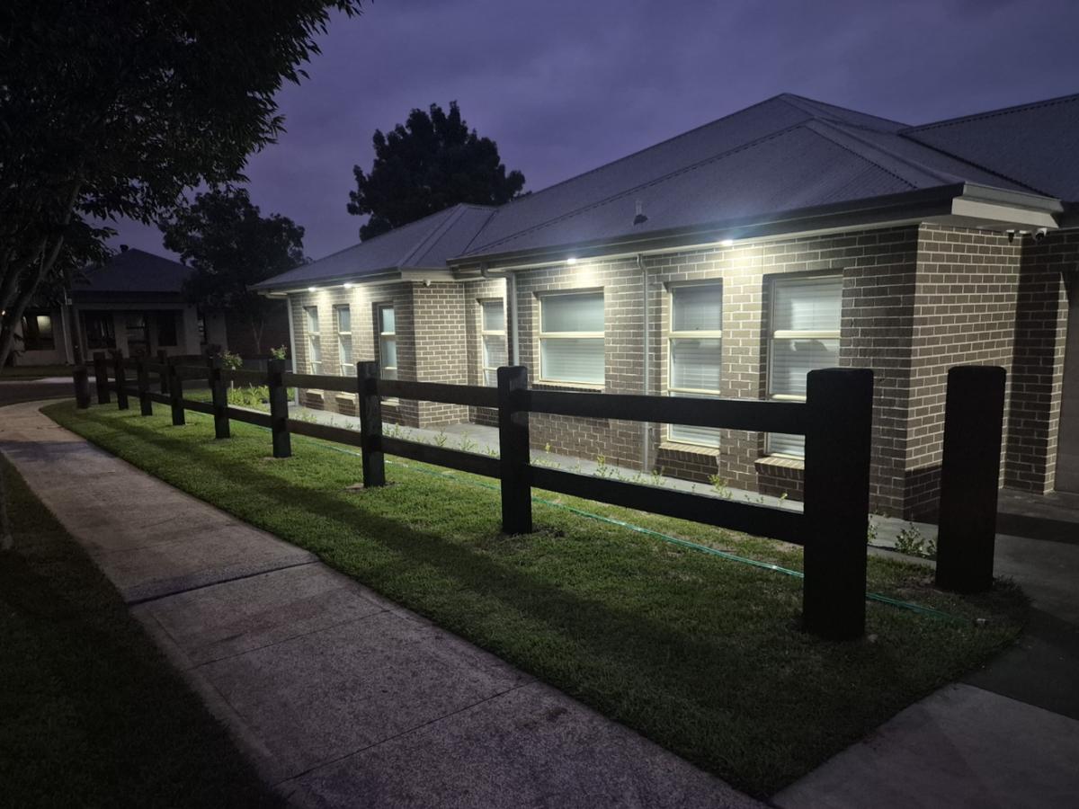 Two rail hardwood fence along a footpath at night
