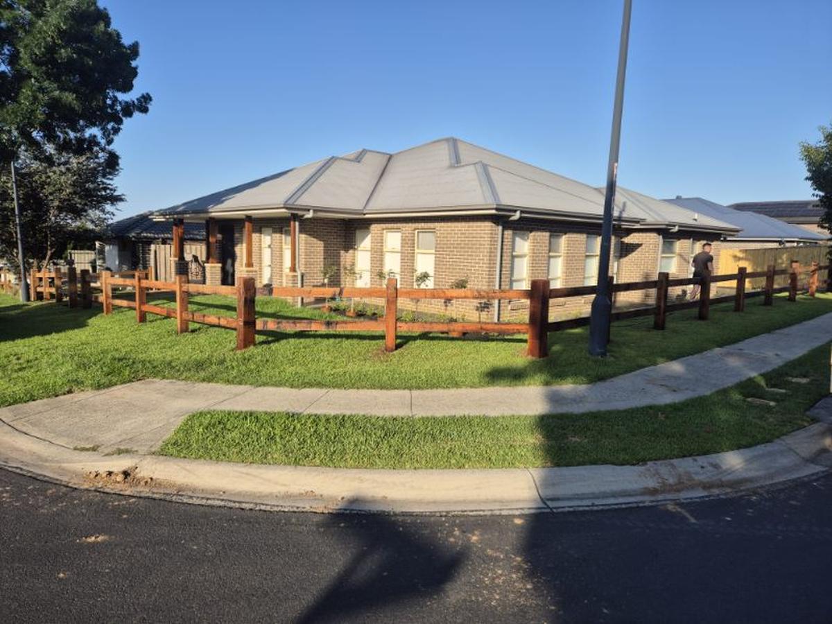 Hardwood post and rail fence around a brick home on a corner block