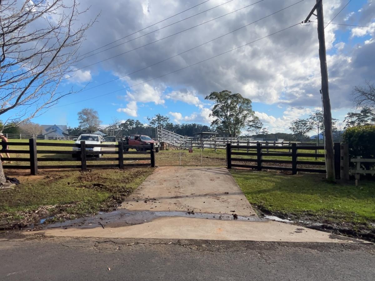 Dark stained post and rail fence either side of a rural driveway entry