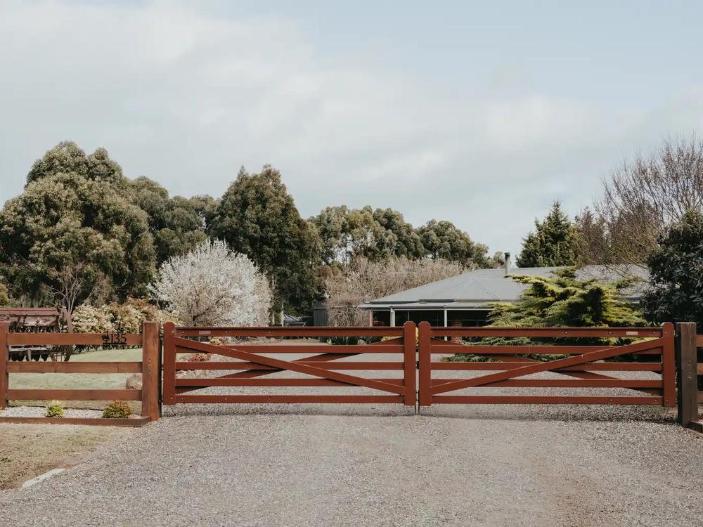 Timber entry gate pair across a gravel driveway