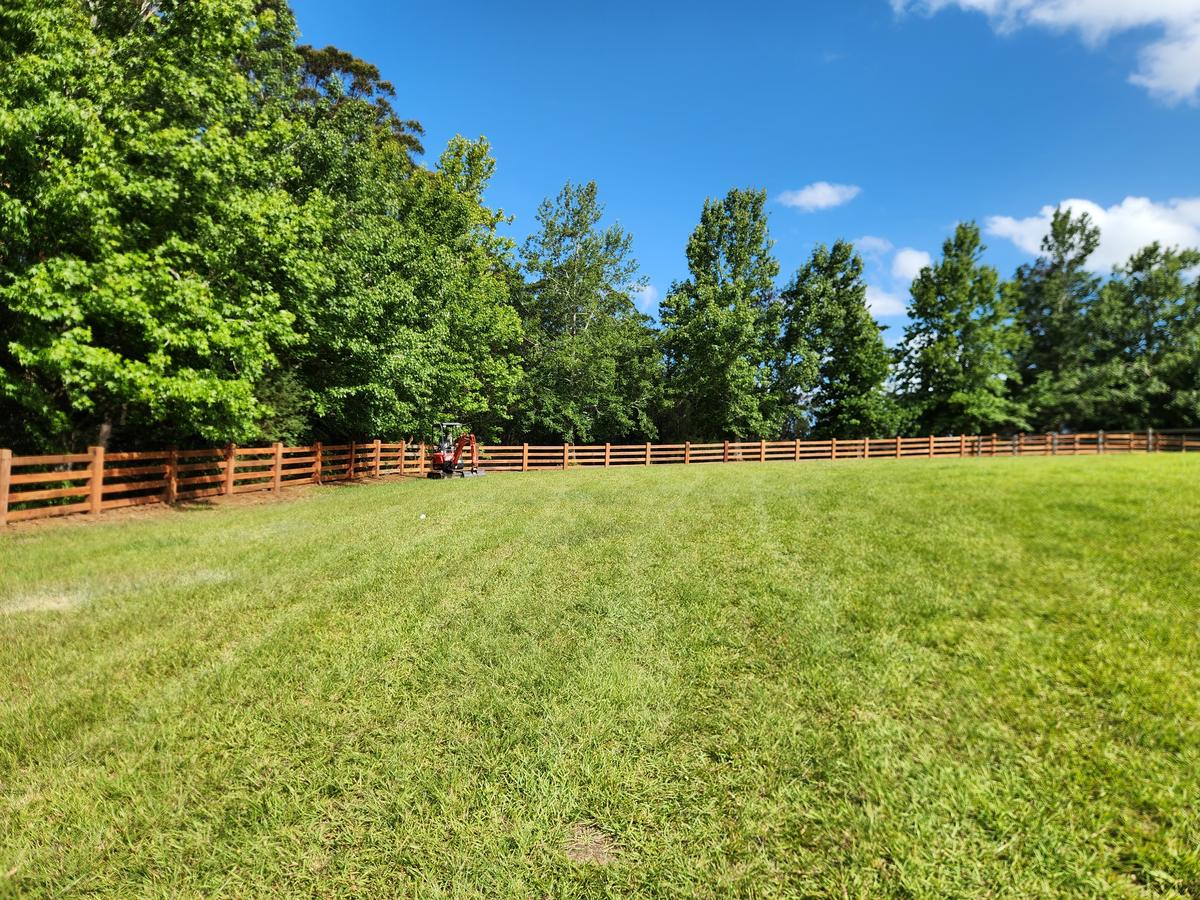 Long four rail hardwood fence curving around a paddock