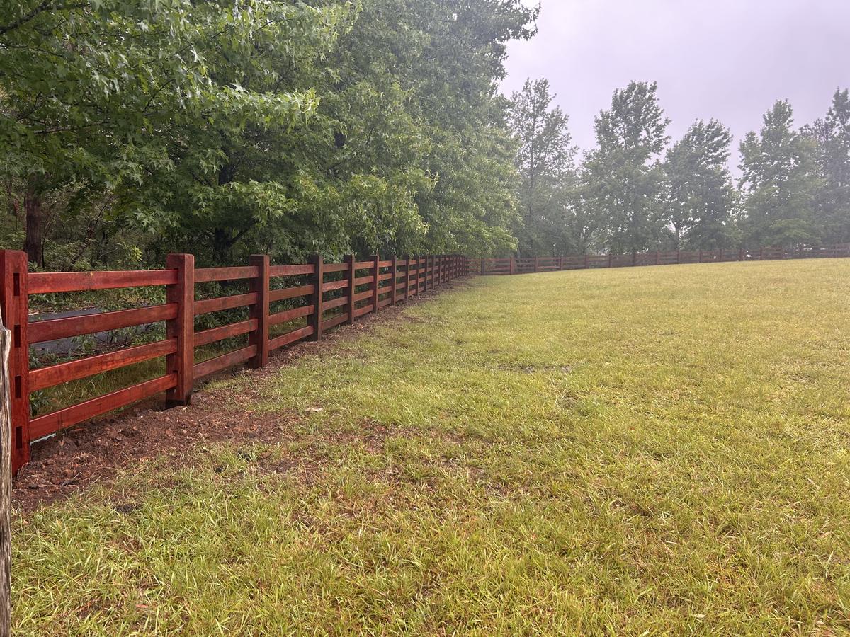 Dark stained four rail fence running through morning mist