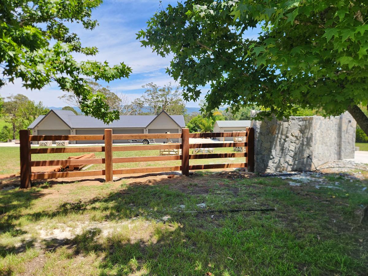 Hardwood post and rail entry beside a stone pillar